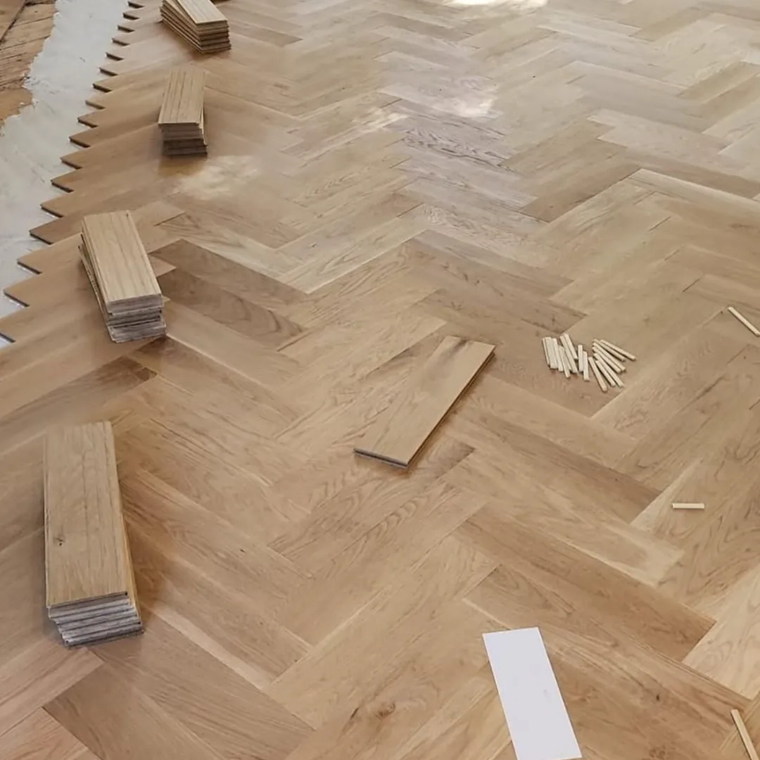 Herringbone hardwood floor installation with wood planks.