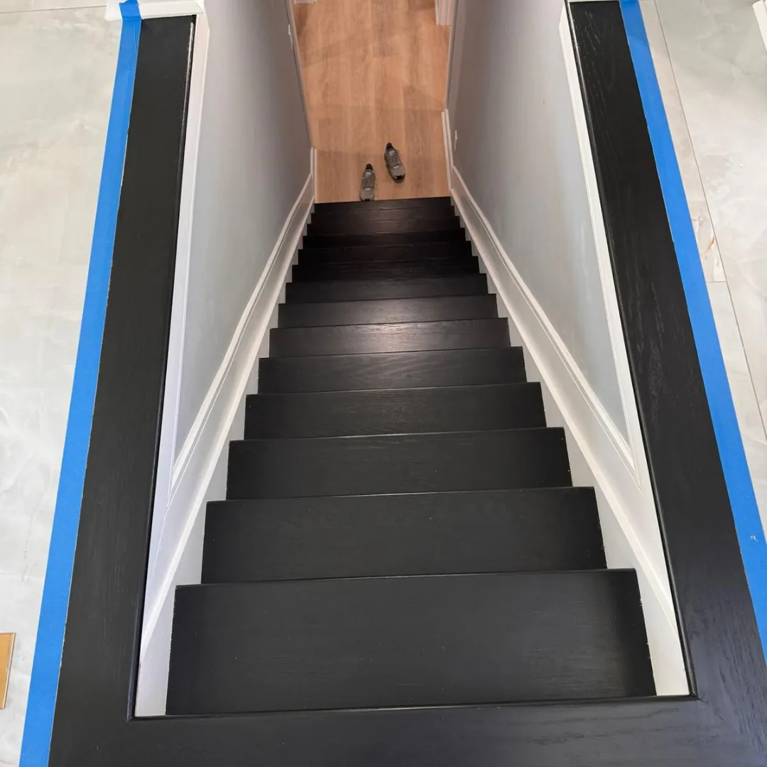 Dark stained staircase during refinishing with protective taping